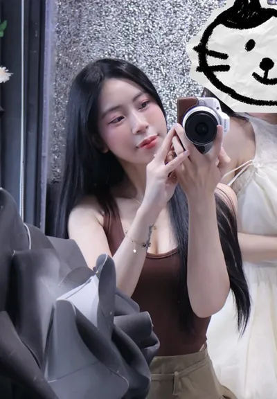 A young woman holding a camera while taking a photo