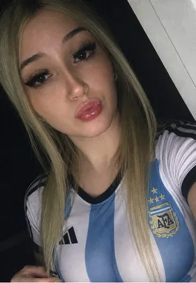 A blonde woman wearing an Argentina national team jersey taking a selfie