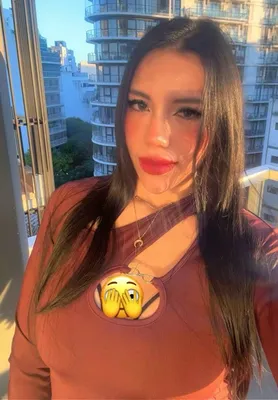 A woman on a video call from a city apartment with high-rise buildings behind her